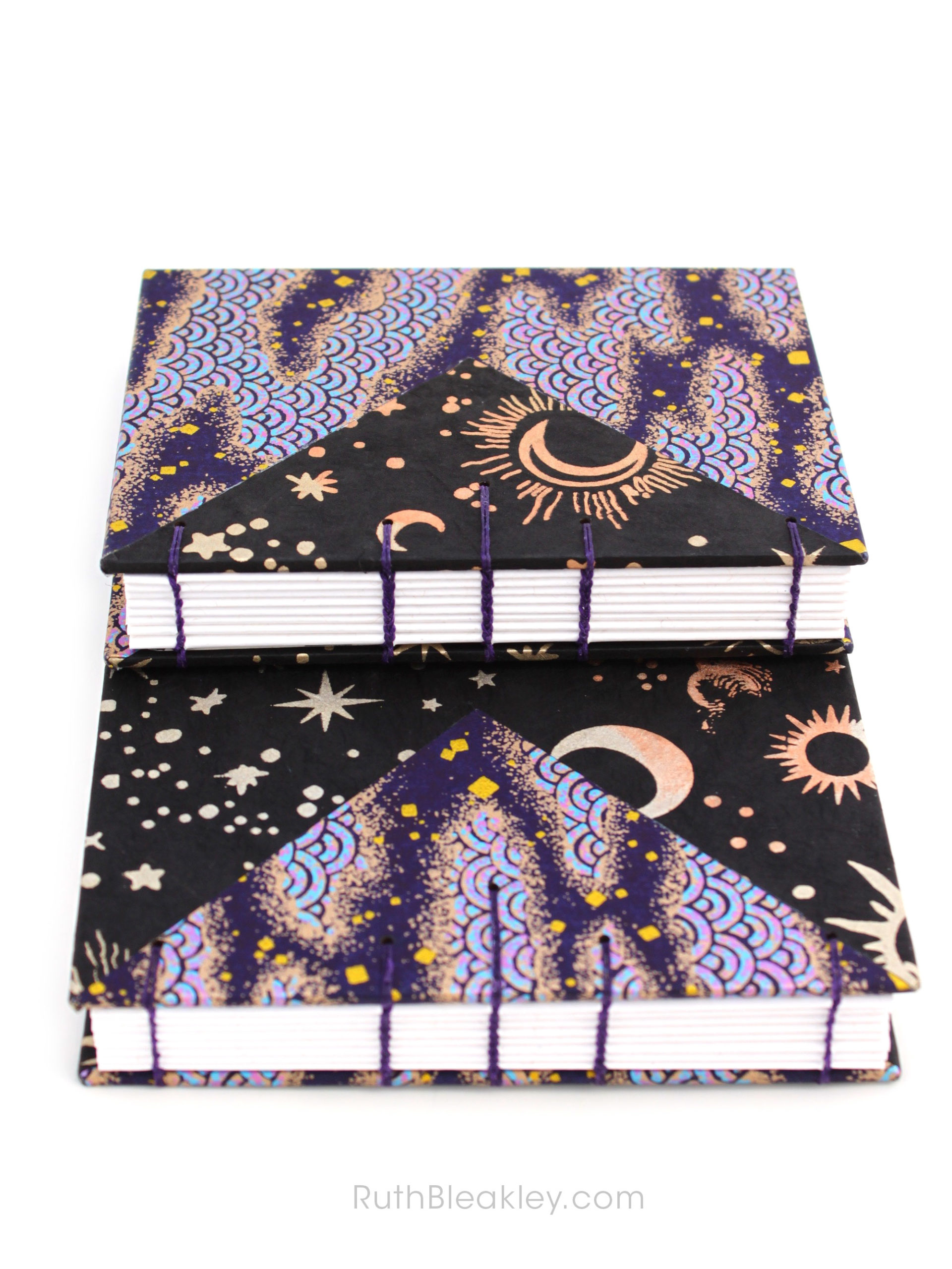 Two black and purple handmade journals by Ruth Bleakley with cosmic imagery