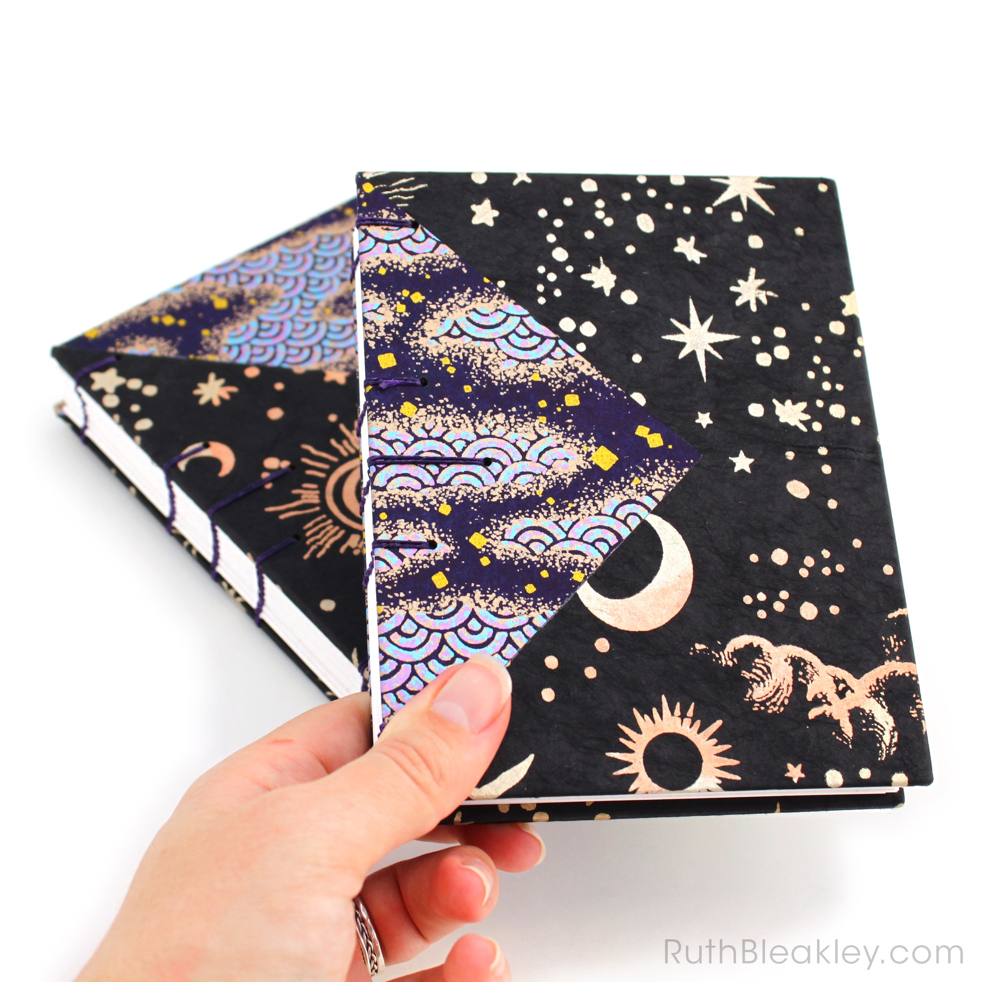 Two black and purple handmade journals by Ruth Bleakley with cosmic imagery